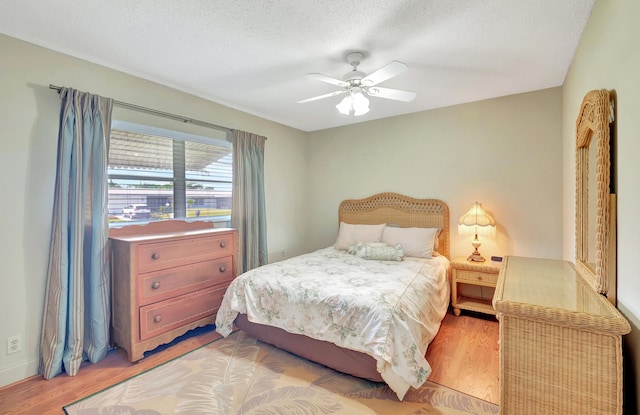 bedroom with ceiling fan, a textured ceiling, and light hardwood / wood-style floors