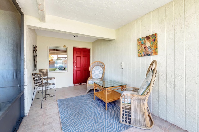 sitting room featuring beam ceiling, tile patterned floors, and wood walls