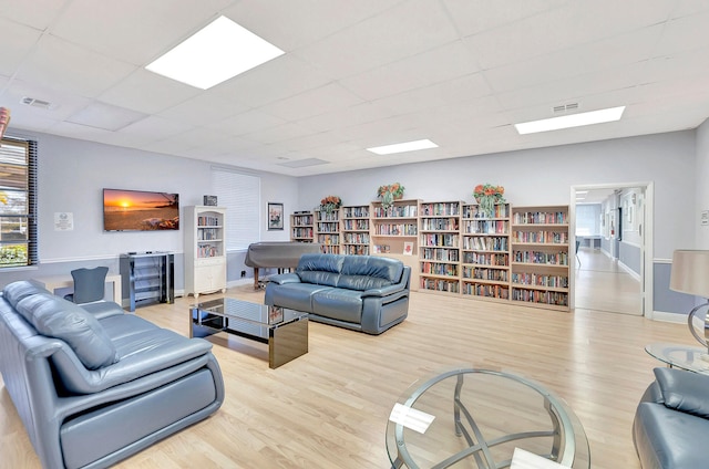 living room with light wood-type flooring and a paneled ceiling