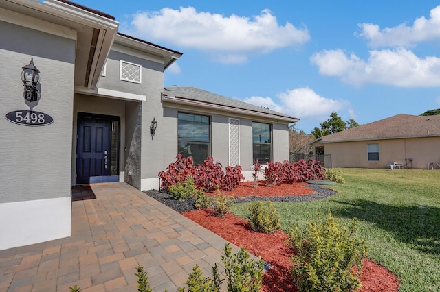 entrance to property with a patio and a lawn