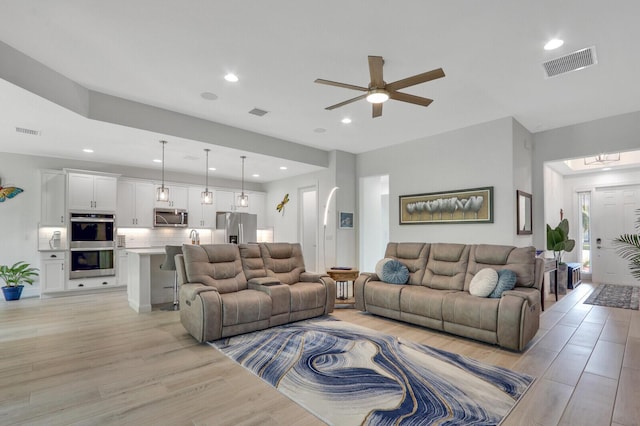 living room featuring light hardwood / wood-style floors and ceiling fan