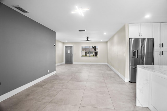 kitchen featuring light stone counters, white cabinetry, stainless steel fridge, and ceiling fan