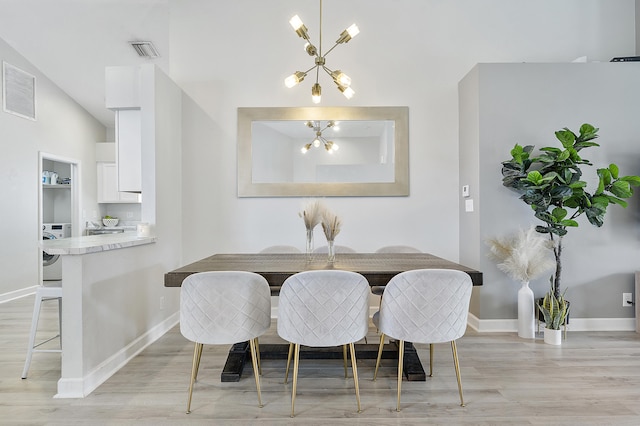 dining room with vaulted ceiling, a notable chandelier, washer / dryer, light hardwood / wood-style floors, and breakfast area