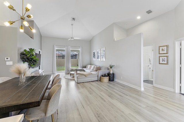 living room with high vaulted ceiling, light wood-type flooring, and ceiling fan with notable chandelier