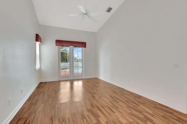 empty room with hardwood / wood-style floors, high vaulted ceiling, ceiling fan, and french doors