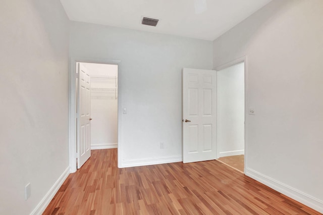 unfurnished bedroom with ceiling fan, light hardwood / wood-style floors, a closet, and a spacious closet