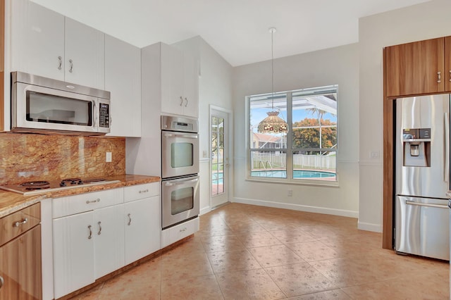 kitchen featuring decorative light fixtures, light stone counters, white cabinets, and stainless steel appliances