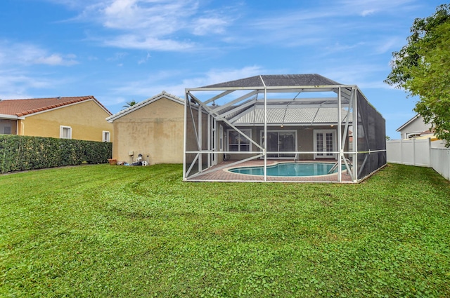 back of property with a fenced in pool, glass enclosure, and a yard