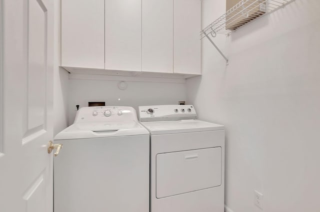 clothes washing area featuring cabinets and washer and dryer