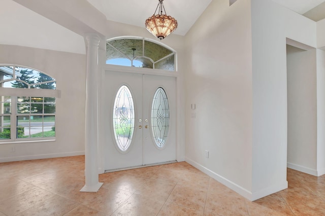 foyer featuring decorative columns, light tile patterned floors, a notable chandelier, and french doors