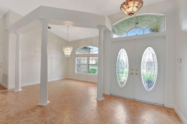 foyer with ornate columns, a wealth of natural light, an inviting chandelier, and light tile patterned floors