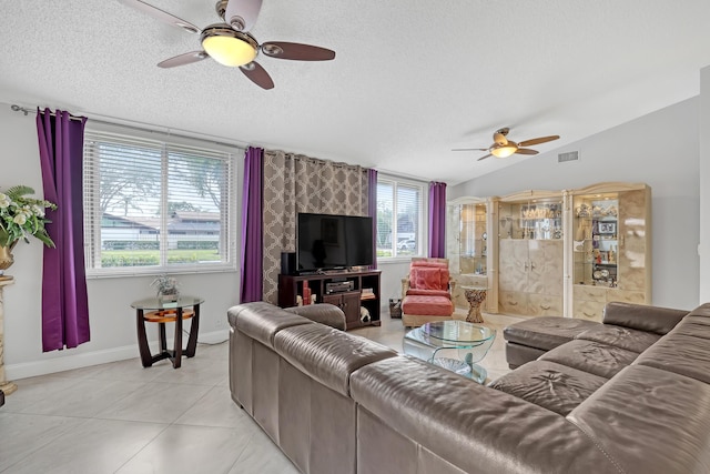 living room with vaulted ceiling, light tile patterned flooring, ceiling fan, and a textured ceiling