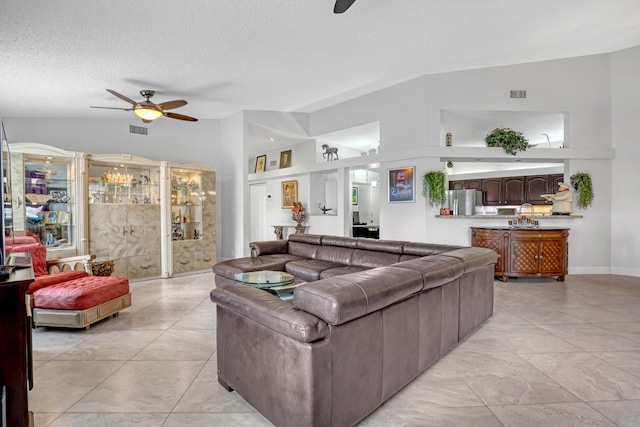 living room featuring lofted ceiling, a textured ceiling, and ceiling fan