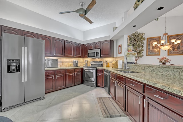 kitchen with pendant lighting, stainless steel appliances, a textured ceiling, and backsplash