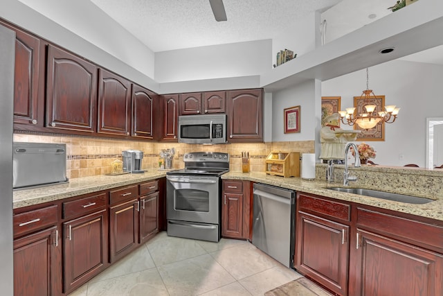 kitchen with pendant lighting, sink, appliances with stainless steel finishes, backsplash, and light stone counters