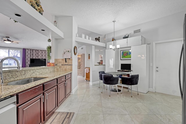 kitchen featuring pendant lighting, tasteful backsplash, dishwasher, sink, and light stone counters