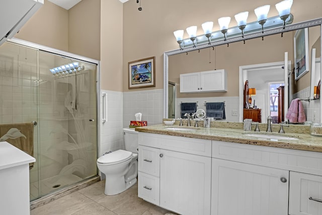 bathroom featuring tile patterned floors, toilet, tile walls, vanity, and a shower with door