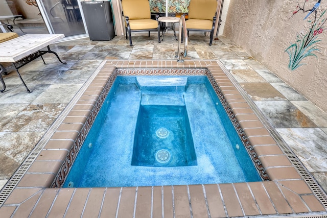 view of swimming pool featuring an in ground hot tub and a patio