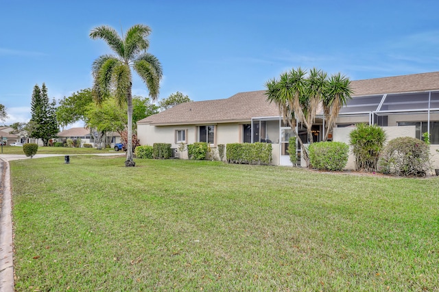 view of front of property with a front yard and glass enclosure