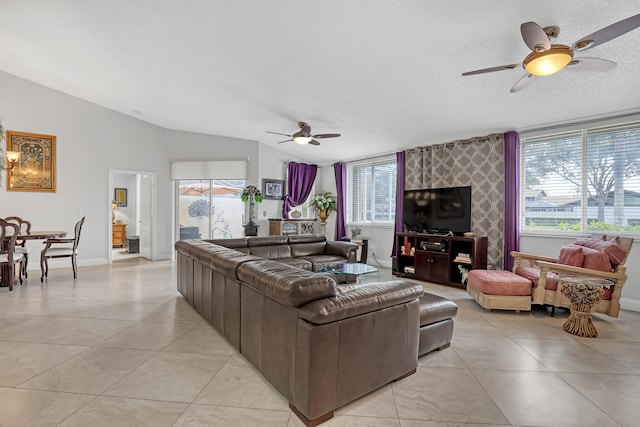 living room with ceiling fan, vaulted ceiling, a textured ceiling, and light tile patterned floors