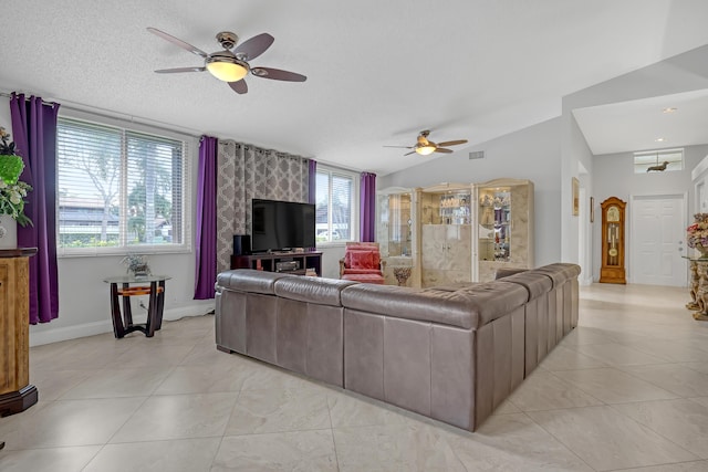 living room with vaulted ceiling, light tile patterned floors, ceiling fan, and a textured ceiling