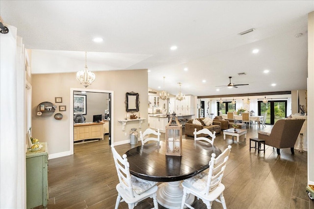 dining room with ceiling fan with notable chandelier, dark wood-type flooring, and vaulted ceiling