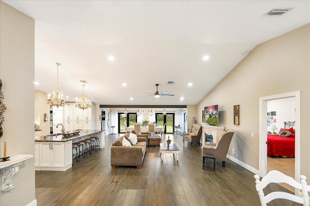 living room featuring ceiling fan with notable chandelier, high vaulted ceiling, and dark wood-type flooring