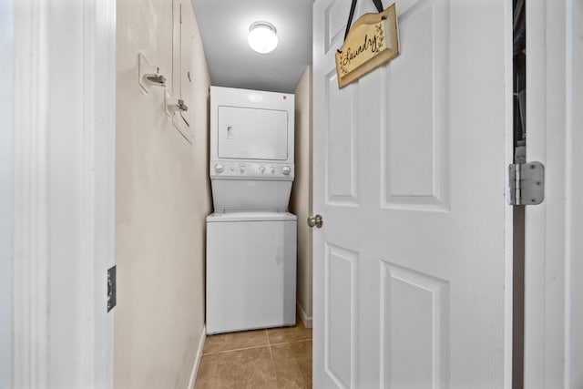 laundry area featuring stacked washer / drying machine and light tile patterned floors