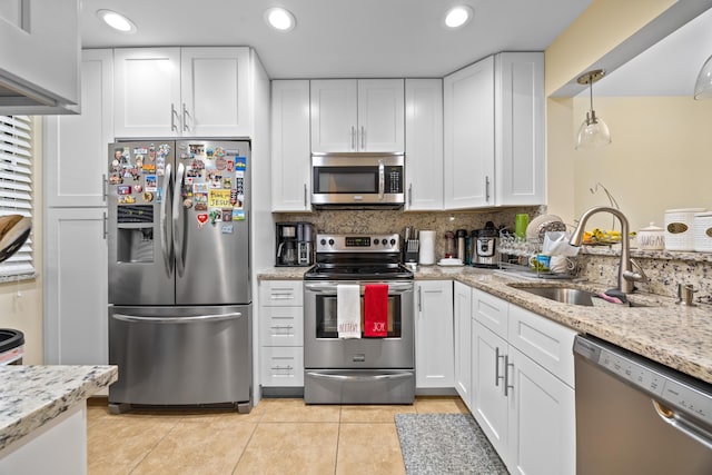 kitchen with white cabinets, appliances with stainless steel finishes, sink, hanging light fixtures, and light tile patterned floors