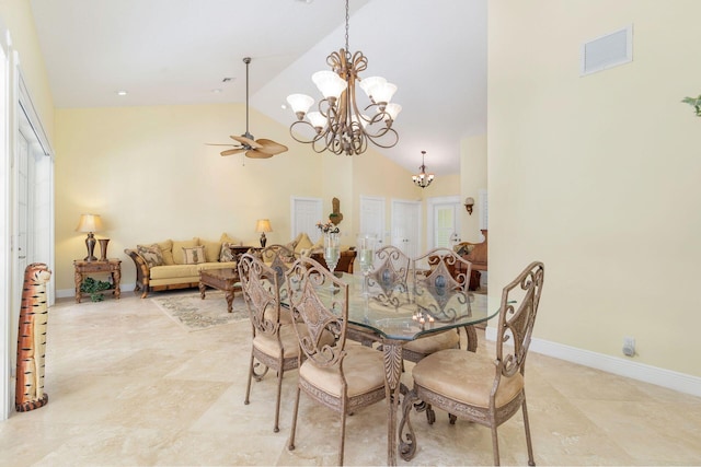 dining space featuring ceiling fan with notable chandelier and high vaulted ceiling