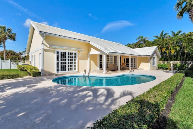 rear view of house with a fenced in pool, a patio, and french doors