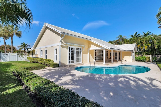 rear view of house with a fenced in pool, a patio area, french doors, and a lawn