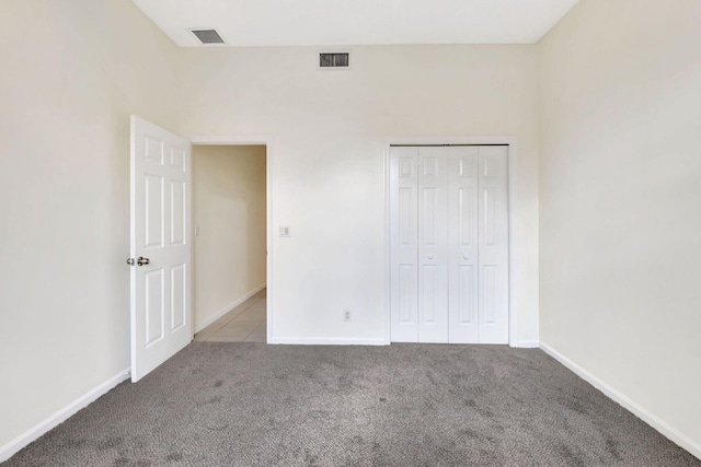 unfurnished bedroom featuring light colored carpet and a closet