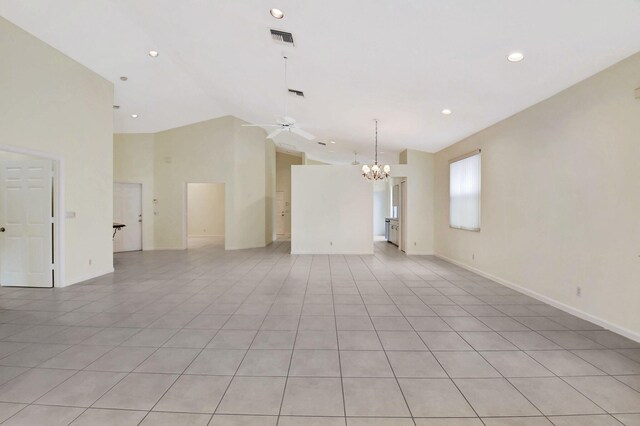 spare room with ceiling fan with notable chandelier, high vaulted ceiling, and light tile patterned flooring