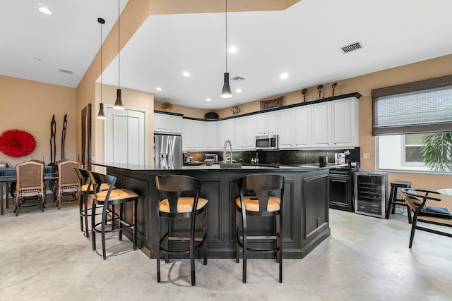 kitchen featuring a large island, decorative light fixtures, appliances with stainless steel finishes, white cabinetry, and beverage cooler