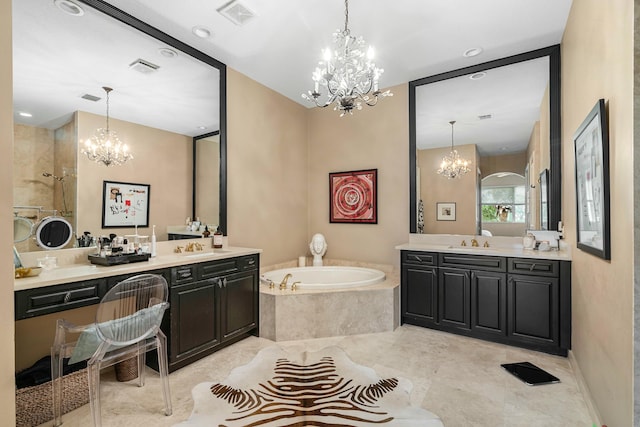 bathroom with an inviting chandelier, tiled tub, and vanity