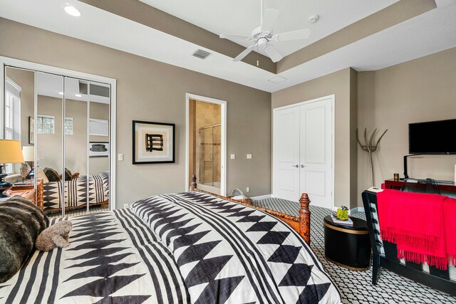 bedroom with connected bathroom, visible vents, a ceiling fan, a closet, and a tray ceiling