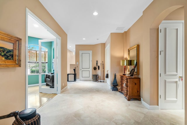 hallway featuring arched walkways, baseboards, and recessed lighting