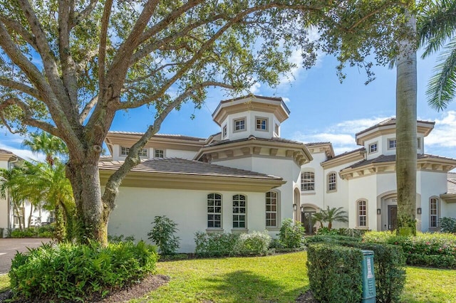 view of front of house featuring a tiled roof, a front lawn, and stucco siding