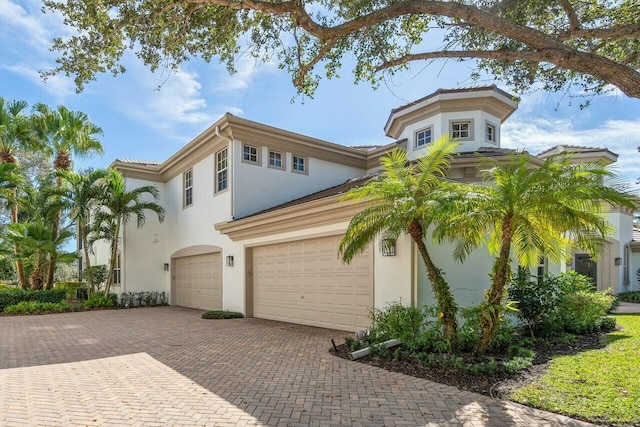 mediterranean / spanish-style home featuring decorative driveway, an attached garage, and stucco siding