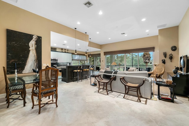 interior space featuring a kitchen bar, hanging light fixtures, and white cabinets