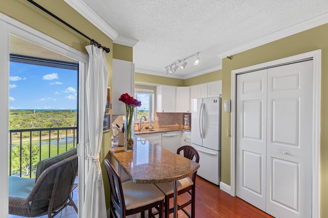 kitchen featuring white appliances, sink, a kitchen breakfast bar, kitchen peninsula, and white cabinets