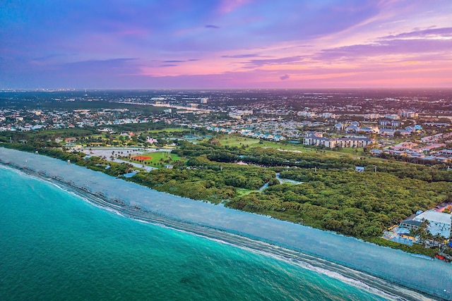 aerial view at dusk with a beach view and a water view