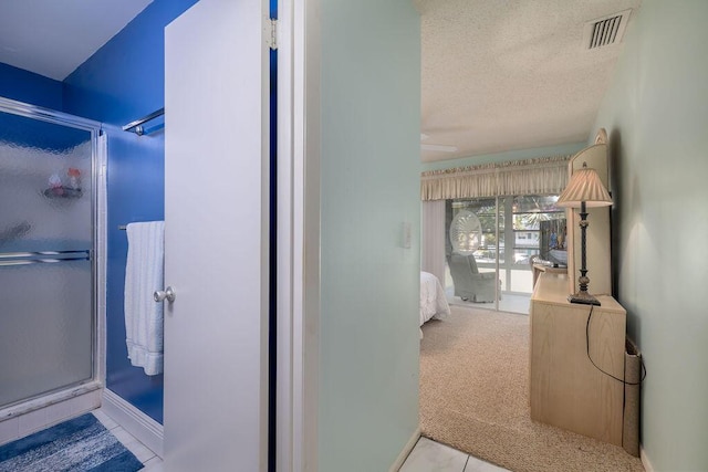 bathroom featuring ceiling fan, tile patterned floors, a shower with door, and a textured ceiling