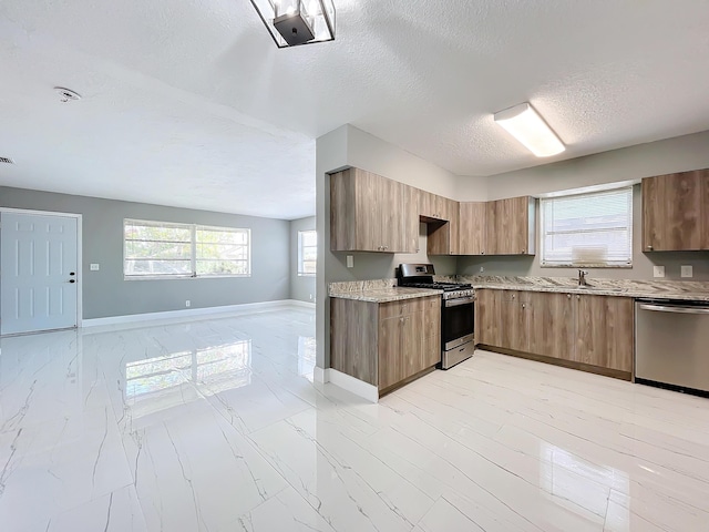 kitchen featuring light stone countertops, sink, stainless steel appliances, and a textured ceiling