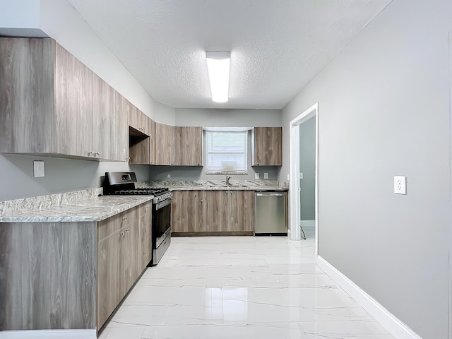 kitchen featuring light stone countertops, appliances with stainless steel finishes, sink, and a textured ceiling