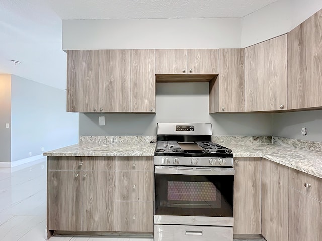 kitchen featuring light brown cabinets, light stone countertops, and gas range