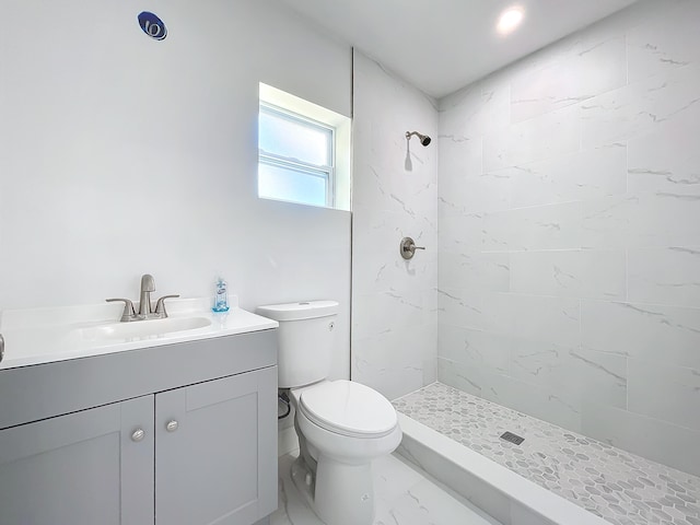 bathroom with toilet, vanity, and tiled shower