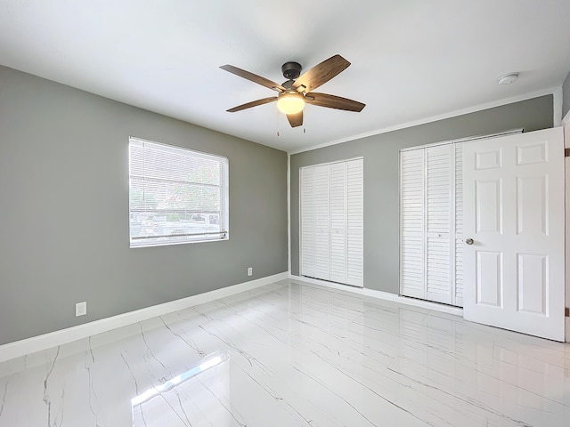 unfurnished bedroom featuring ceiling fan and multiple closets