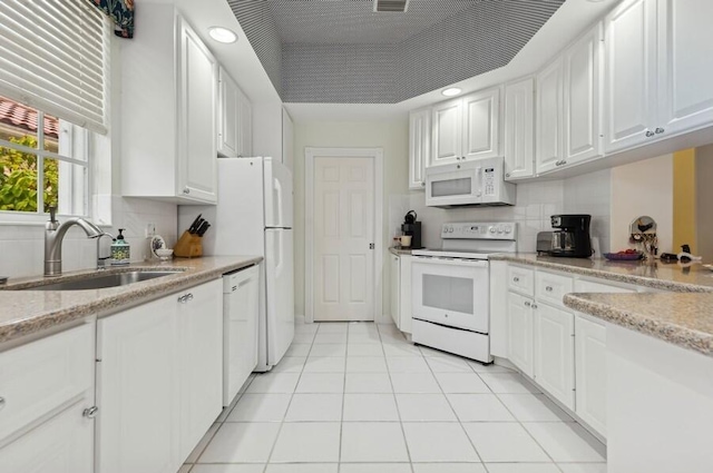 kitchen with sink, white appliances, light stone countertops, and white cabinets